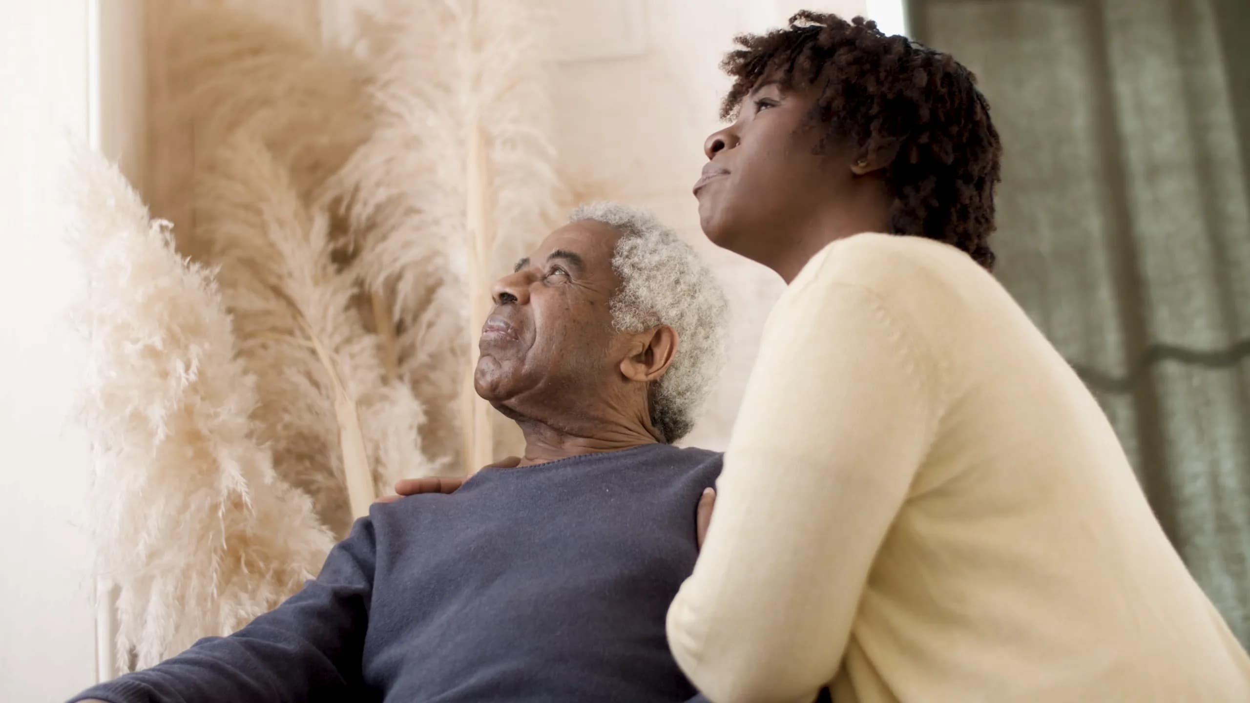 An older man and his carer smiling together